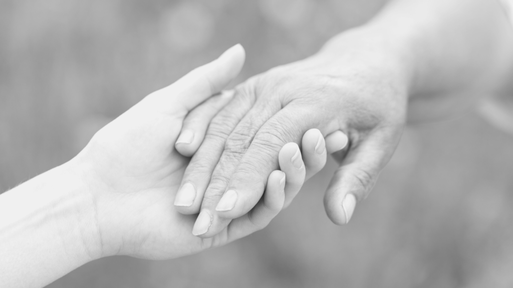 a black and white photo of a hand holding another wrinkly hand