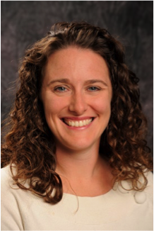 Lauren Troy, a light-skinned woman with brown curly hair and blue eyes, wearing a white top and smiling