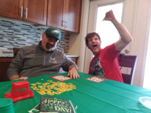 two men sit at a green table playing a board game