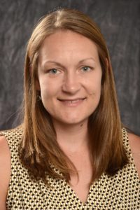 Tracy Kettering, a light-skinned woman with medium length red hair wearing a yellow and black tank top