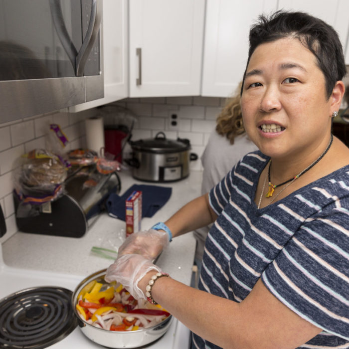 Woman in striped shirt cooking and looking at the camera