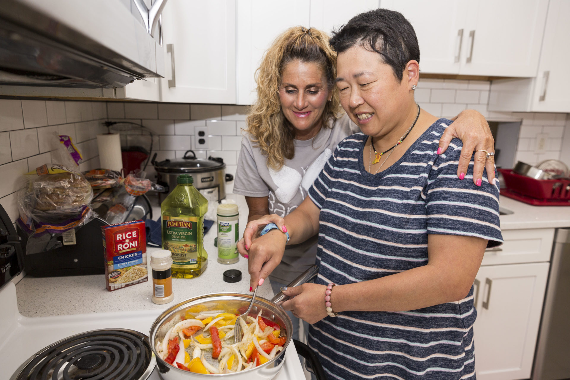 Bancroft Direct Service Professional roasting vegetables on a stovetop in a kitchen with a smiling woman