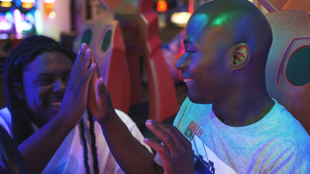 Bancroft boy smiling gives high five to another person smiling at an arcade