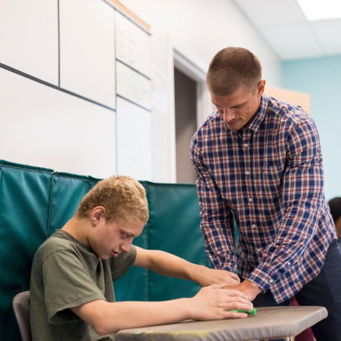 Bancroft Direct Support Professional helping student at desk