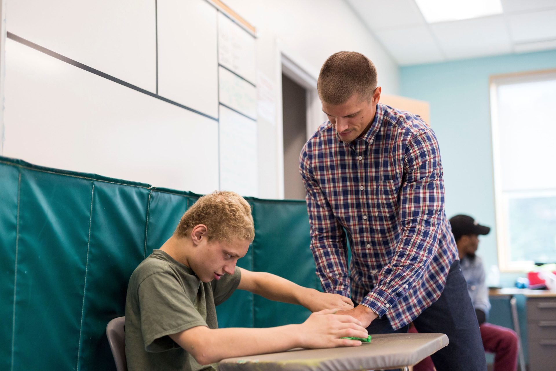 Bancroft Direct Support Professional helping student at desk