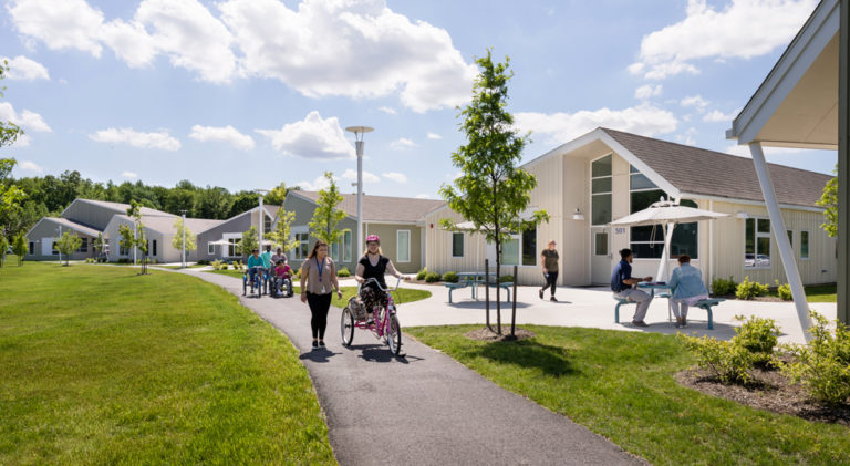 in the Welsh Campus, multiple people walk and ride on a side walk