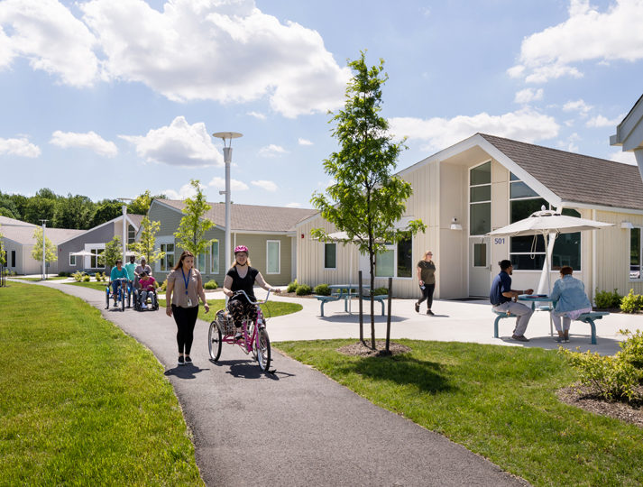 in the Welsh Campus, multiple people walk and ride on a side walk