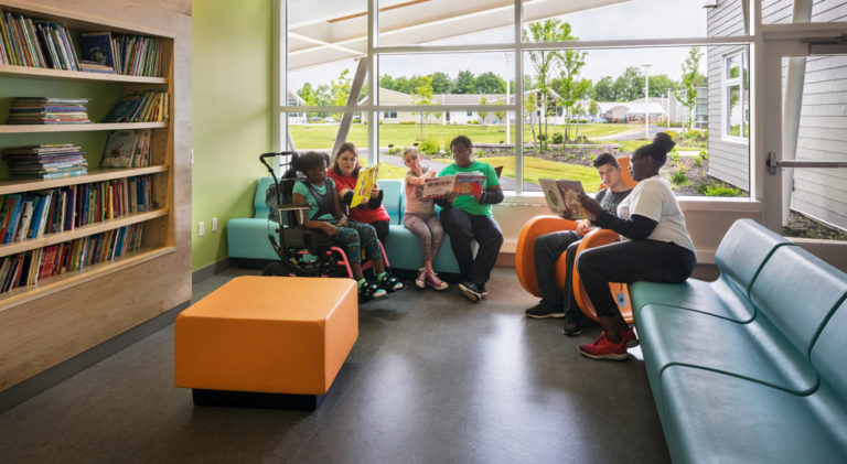 paraprofessionals and people we serve ait on couches in a lobby reading books