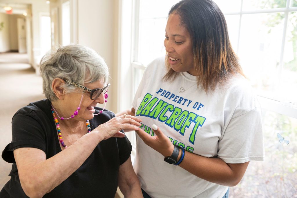 Female paraprofessional in a white shirt interacts with a female resident in a black shirt