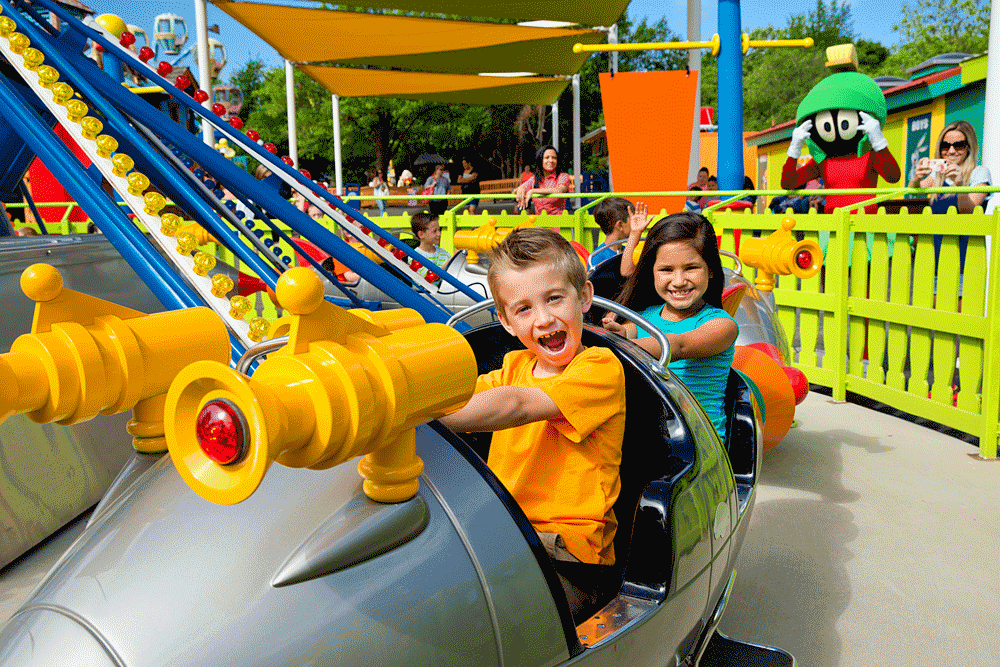 A boy with an orange shirt and a girl with a blue shirt smiling on a rollercoaster