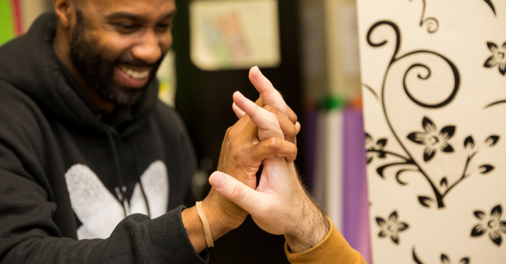 Male paraprofessional in Bancroft sweatshirt giving a high five to another male.