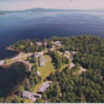 Property in Maine with large trees, a big green yard, and houses surrounded by blue ocean water
