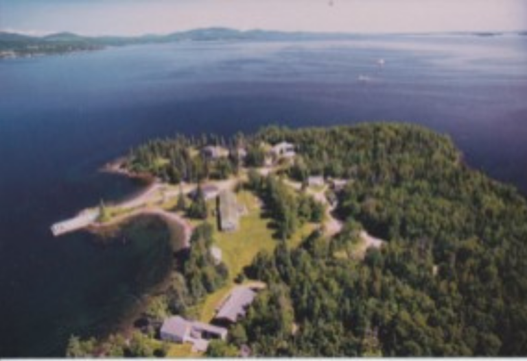 Property in Maine with large trees, a big green yard, and houses surrounded by blue ocean water