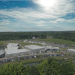 overlook of Bancroft's Mt Laurel campus; a group of grey buildings with white roofs and details in a semi-circle around a parking lot and green lawn