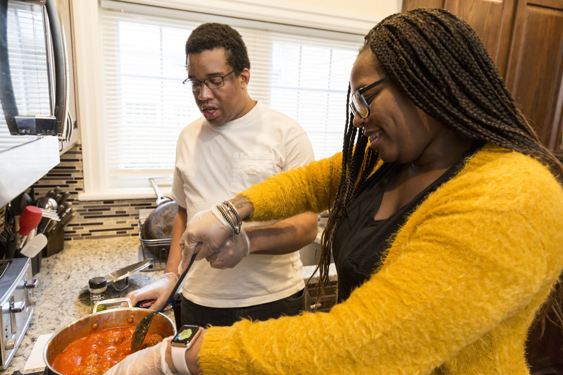 Female paraprofessional helping an individual cook at the stove.