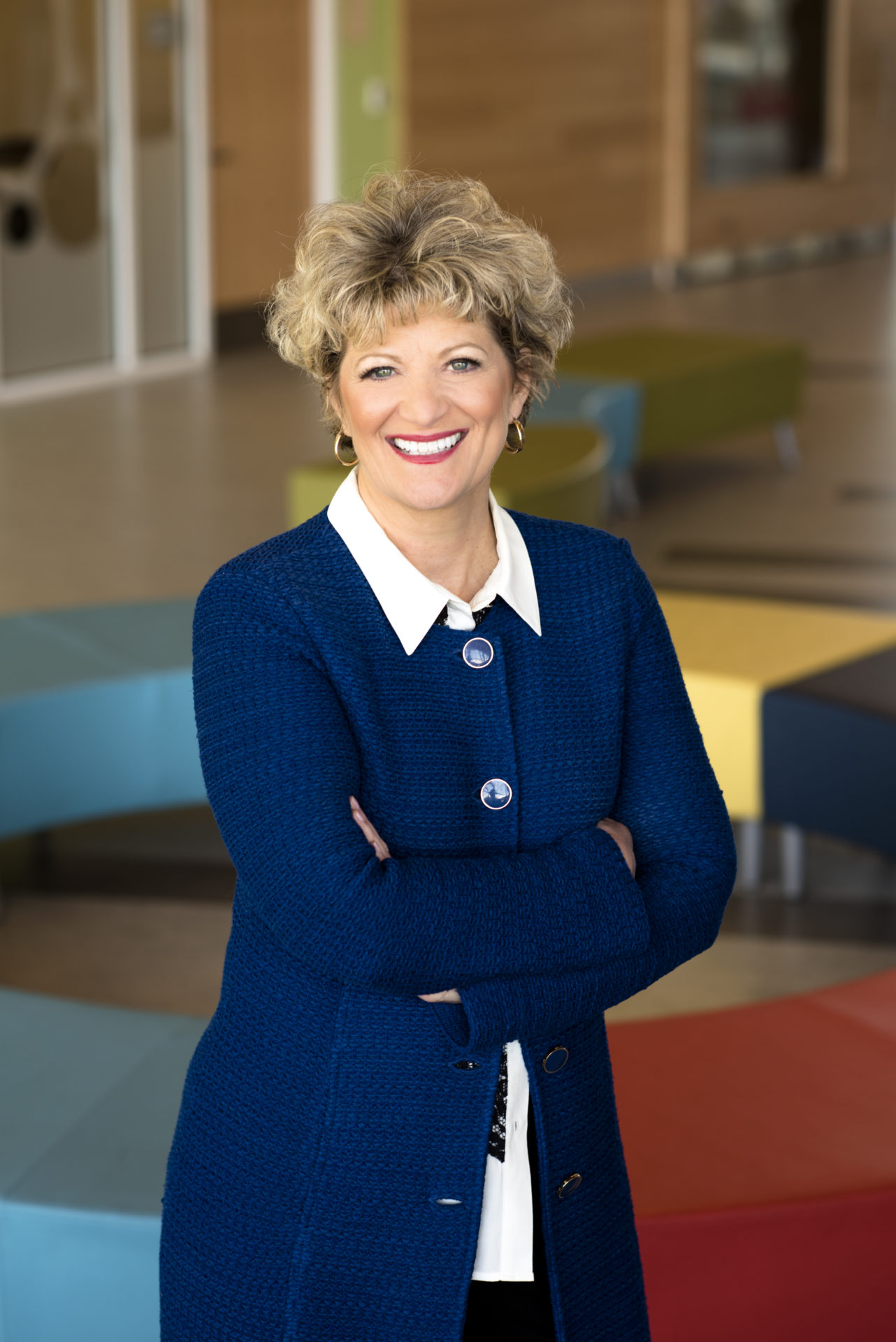 Toni Peroglin, Bancroft's President and CEO, stands in a Bancroft building wearing a blue suit with a button down shirt