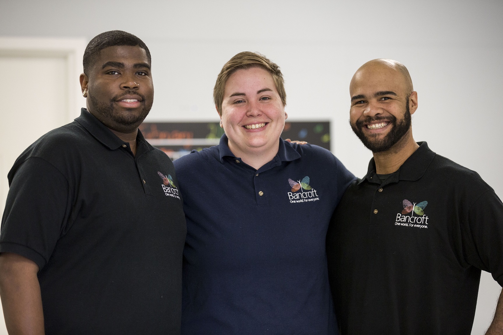 three paraprofessionals in their Bancroft polos stand together and smile