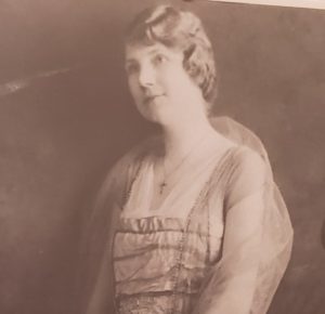 Jenzia Cooley, a light-skinned woman with short hair wearing a long dress smiles