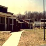 Original Mullica Hill Campus with five dark red buildings with white details connected by a sidewalk