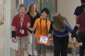 Student holding hands with teacher laughing walking down school hallway