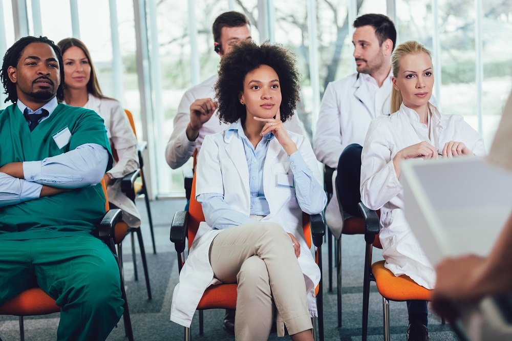 Group of healthcare professionals seated watching training presentation