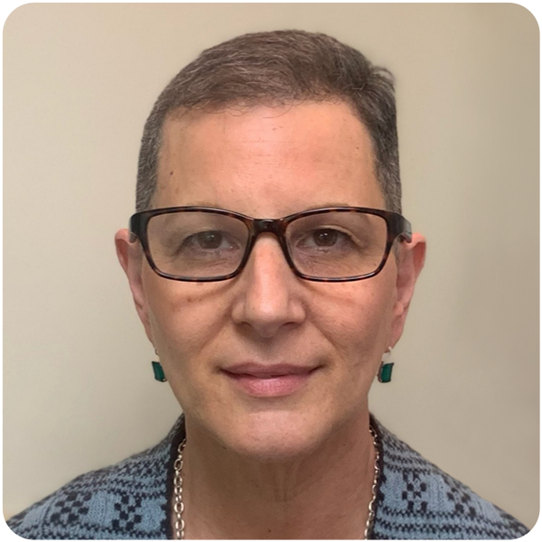 Karen Reiss, light-skinned woman with gray-brown hair, broung classes, green earrings, and a blue and black top