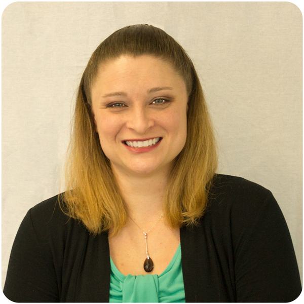 Misty Simmons, a light-skinned blonde woman wearing a green blouse and black shawl smiles