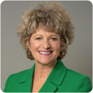 Toni Pergolin's headshot where she is smiling and wearing a green blazer jacket