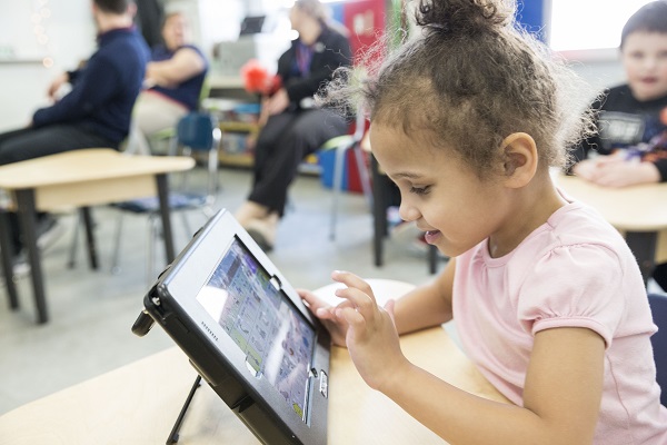 Young student sitting at desk using assistive technology ipad