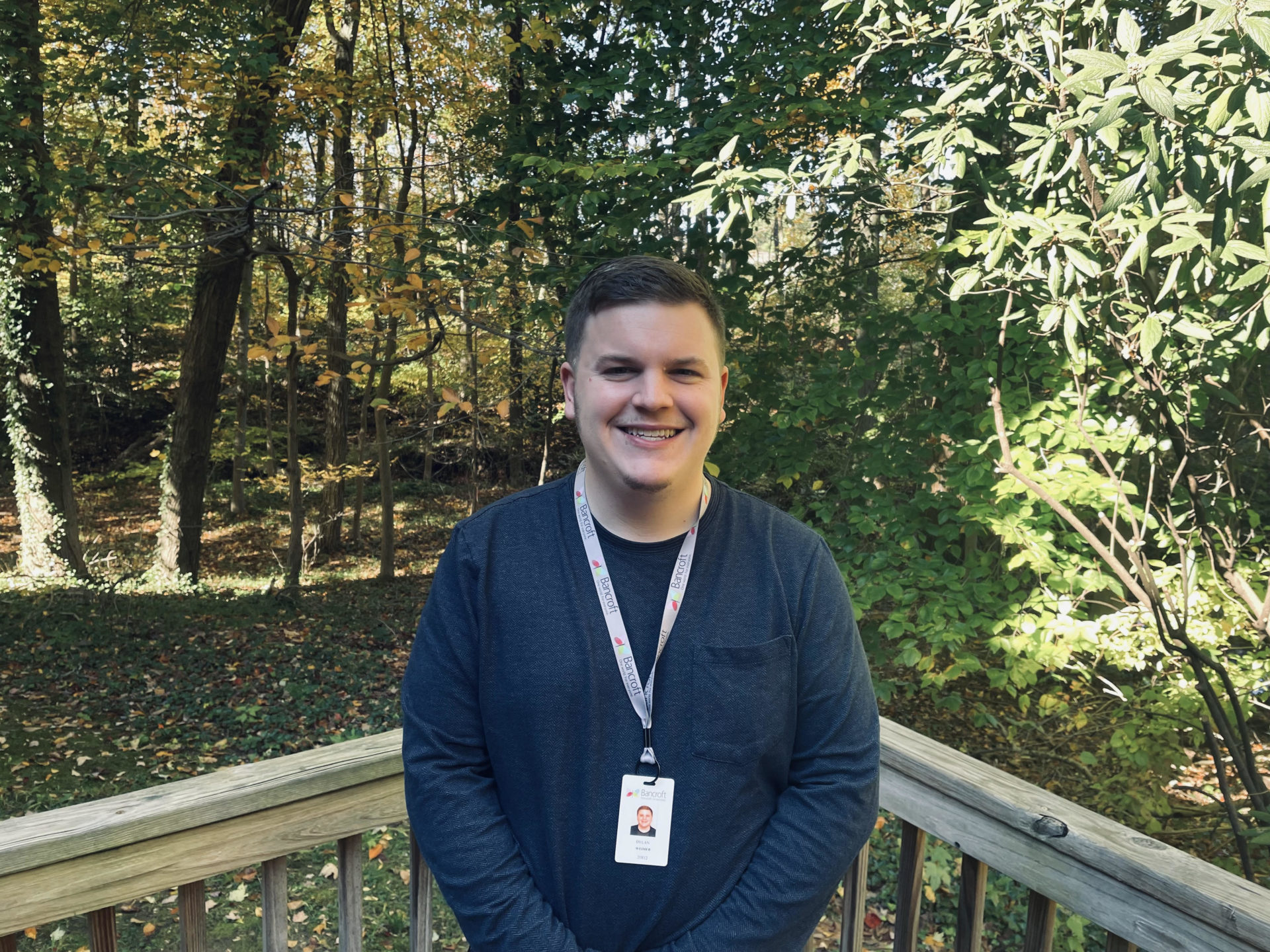 A light skinned male is standing outside and smiling.