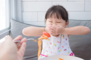 Young Asian girl refuses to eat spaghetti