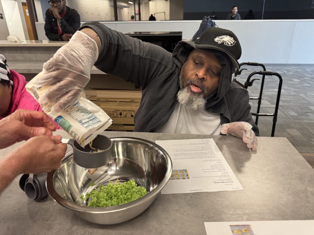 Participant pours cheese into bowl, making broccoli cheddar bites