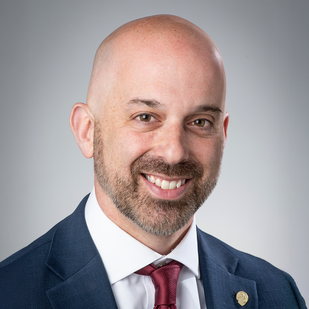 Gregory Passanante, President and CEO of Bancroft, smiling in a professional headshot wearing a navy suit and red tie