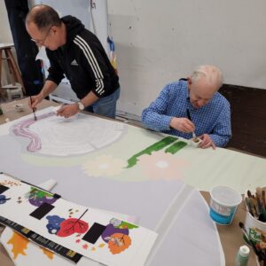 Two individuals painting elements for the mural