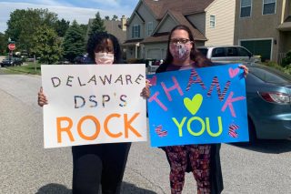 Two adult women standing and holding signs. One sign says "Thank you DSP" and the other sign says "DSPs Rock!"