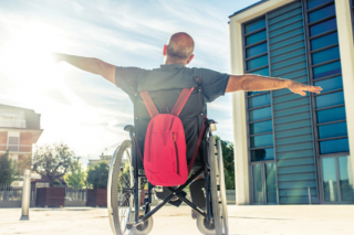 Man in wheelchair stretching his arms out