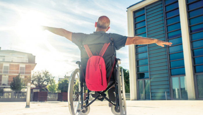 Man in wheelchair stretching his arms out