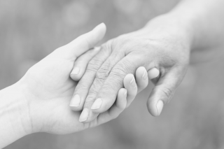 a black and white photo of a hand holding another wrinkly hand