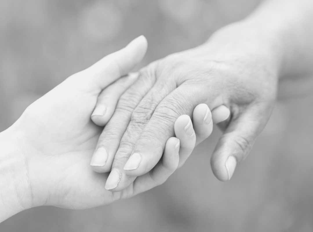 a black and white photo of a hand holding another wrinkly hand