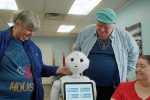 group of residents of Bancroft's Flicker residential program for older adults with autism and other I/DD stand with Pepper, the humanoid AI robot