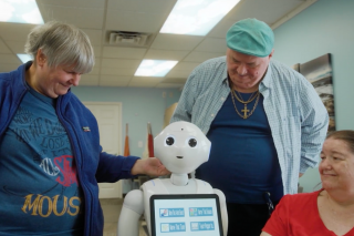 group of residents of Bancroft's Flicker residential program for older adults with autism and other I/DD stand with Pepper, the humanoid AI robot