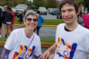 A mother and her adult son are wearing matching white t-shirts and are smiling at the camera. Her son is a resident in a Bancroft adult group home.