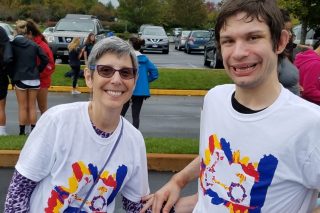 A mother and her adult son are wearing matching white t-shirts and are smiling at the camera. Her son is a resident in a Bancroft adult group home.
