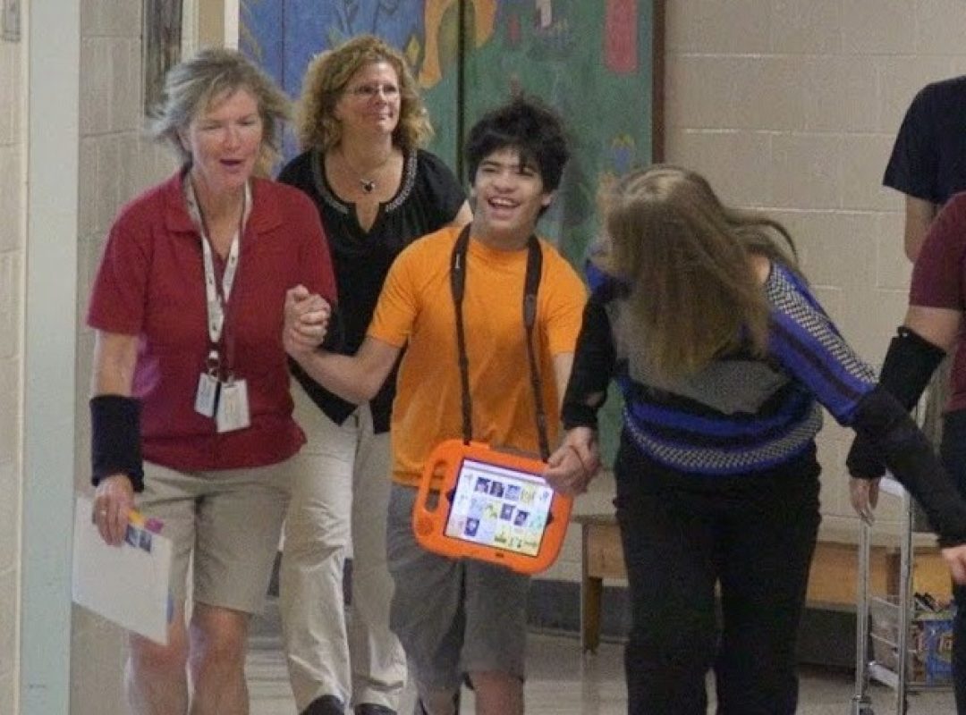 Student holding hands with teacher laughing walking down school hallway