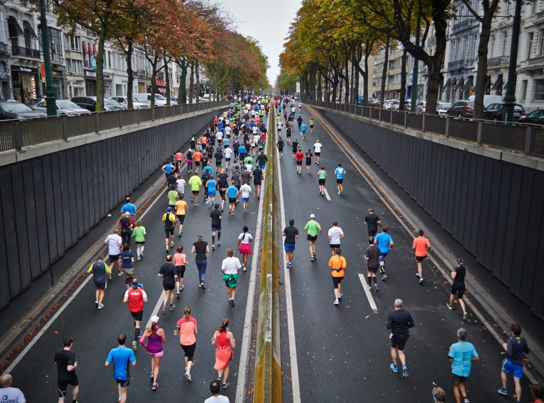 dozens of people run down a street