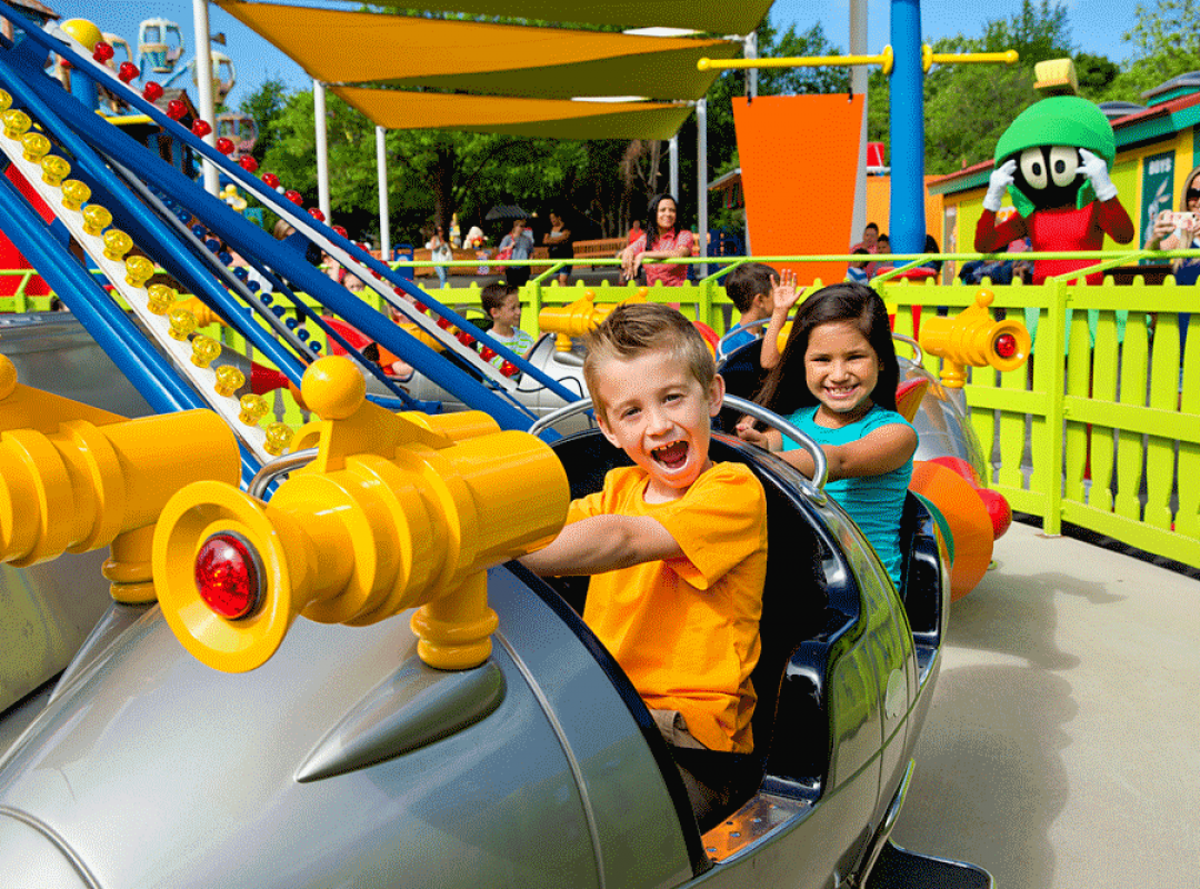 A boy with an orange shirt and a girl with a blue shirt smiling on a rollercoaster