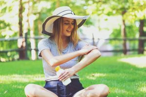 Young woman a bottle of sunblock outside