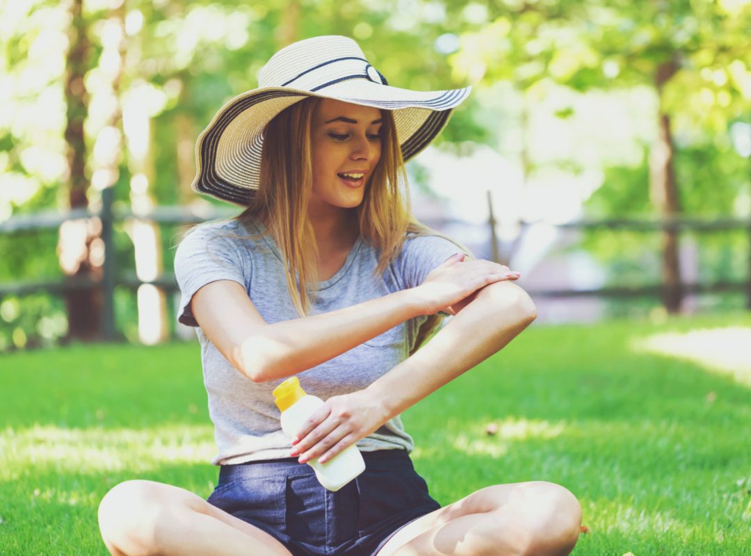 Young woman a bottle of sunblock outside